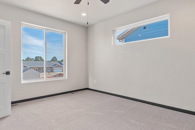 unfurnished room with plenty of natural light, light colored carpet, and ceiling fan