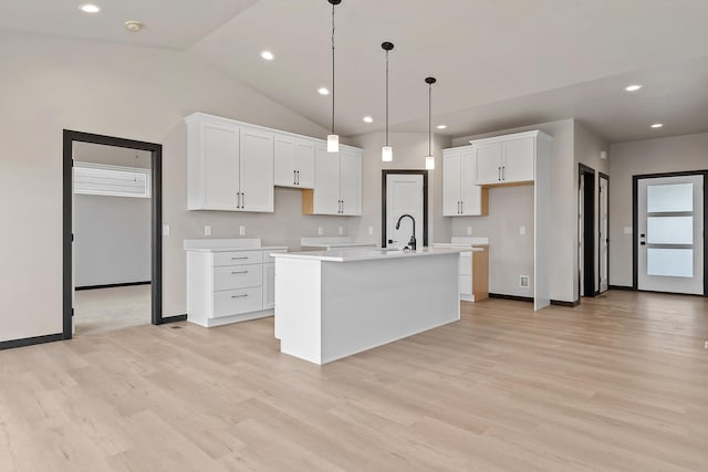 kitchen featuring pendant lighting, sink, light hardwood / wood-style flooring, white cabinetry, and a center island with sink