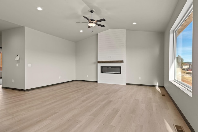 unfurnished living room featuring vaulted ceiling, a large fireplace, ceiling fan, and light wood-type flooring