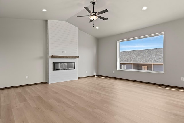 unfurnished living room featuring ceiling fan, lofted ceiling, a fireplace, and light hardwood / wood-style flooring