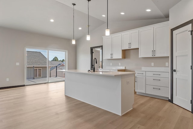 kitchen with white cabinetry, sink, decorative light fixtures, and an island with sink