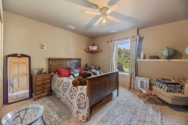 carpeted bedroom with ceiling fan and a textured ceiling