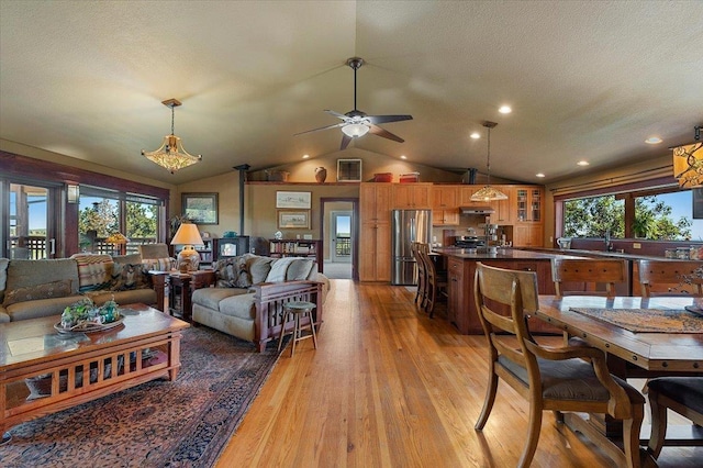 living room with lofted ceiling, a healthy amount of sunlight, light wood-type flooring, and ceiling fan