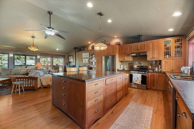 kitchen with appliances with stainless steel finishes, vaulted ceiling, sink, pendant lighting, and light hardwood / wood-style flooring