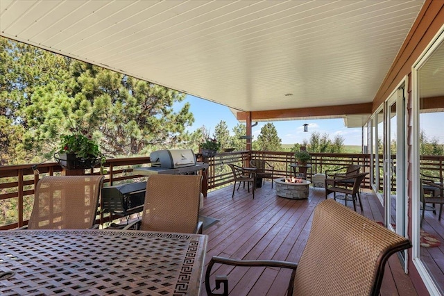 wooden terrace featuring a grill and a fire pit