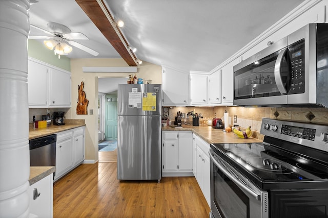 kitchen with appliances with stainless steel finishes, light hardwood / wood-style floors, backsplash, and beamed ceiling