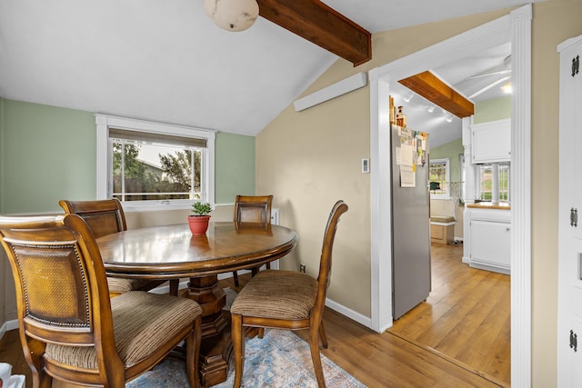 dining space featuring plenty of natural light, lofted ceiling with beams, and light hardwood / wood-style flooring