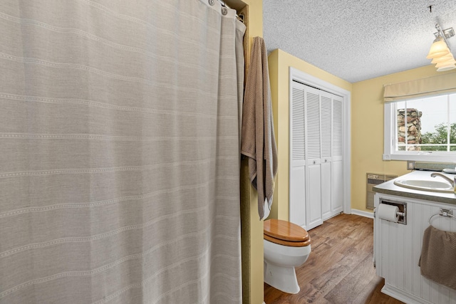 bathroom with a textured ceiling, hardwood / wood-style floors, toilet, and vanity