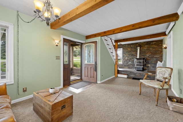 living room featuring beam ceiling, an inviting chandelier, a wood stove, and carpet floors