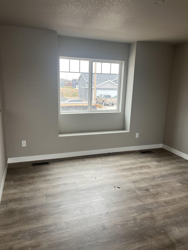 spare room featuring hardwood / wood-style floors and a textured ceiling