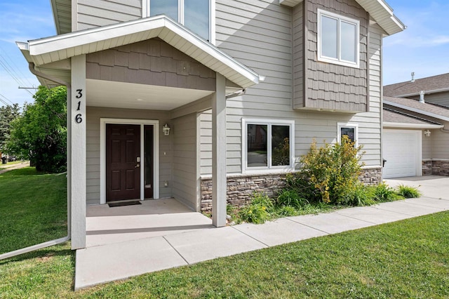 entrance to property with a garage and a lawn