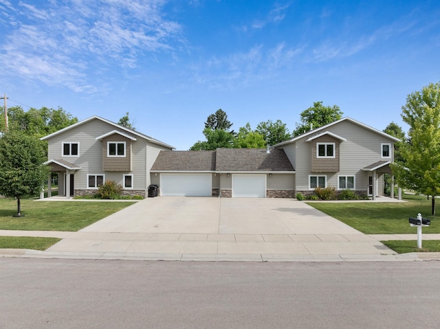 view of property featuring a garage and a front lawn