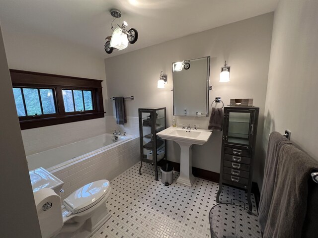 bathroom featuring tile flooring, a washtub, sink, and toilet