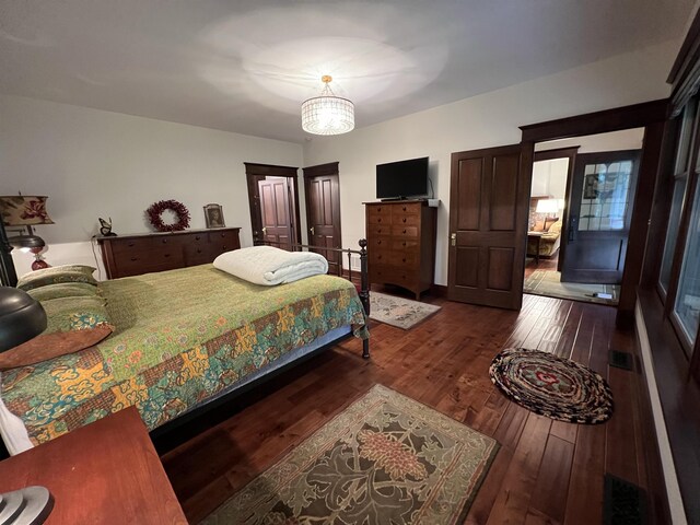 bedroom with dark wood-type flooring and an inviting chandelier