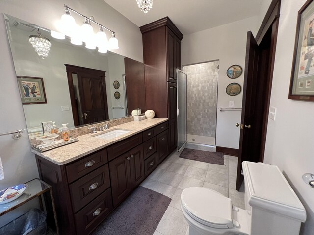 bathroom with tile flooring, a shower with shower door, a chandelier, vanity, and toilet