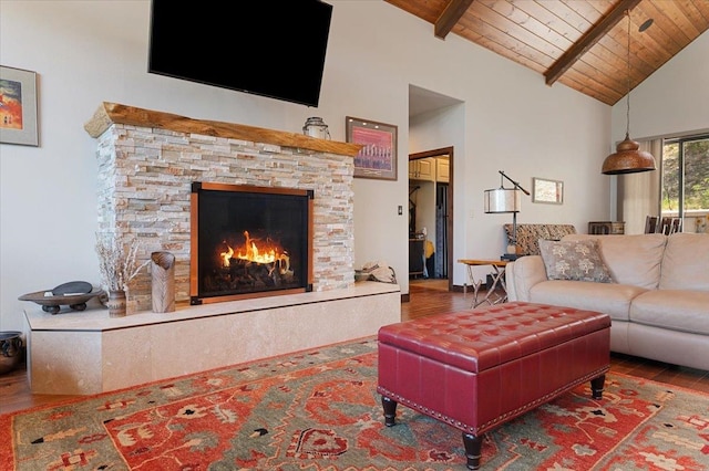 living room featuring beamed ceiling, dark hardwood / wood-style flooring, a stone fireplace, and wood ceiling