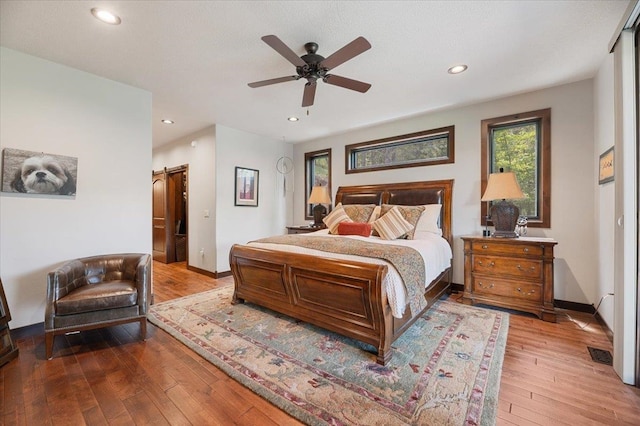 bedroom featuring a barn door, light wood-type flooring, and ceiling fan