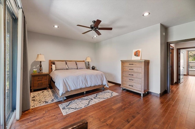 bedroom with a textured ceiling, ceiling fan, and dark hardwood / wood-style floors