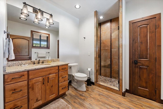 bathroom featuring a shower with shower door, vanity, hardwood / wood-style flooring, and toilet