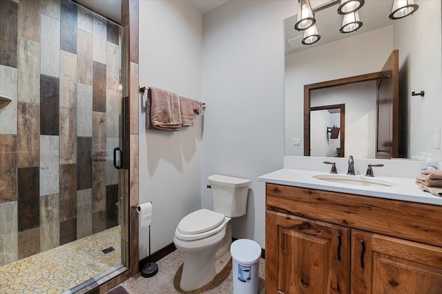 bathroom featuring a shower with shower door, vanity, and toilet