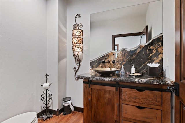 bathroom featuring decorative backsplash, toilet, hardwood / wood-style floors, and vanity