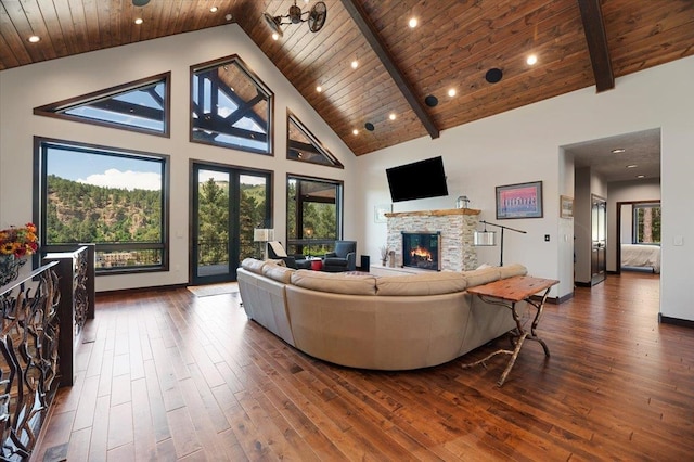 living room with beam ceiling, a stone fireplace, high vaulted ceiling, and wood ceiling