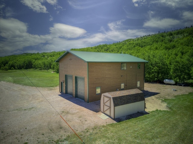 view of property exterior featuring a yard, a garage, and a storage shed