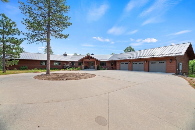 view of front of property with a garage, curved driveway, metal roof, and a standing seam roof