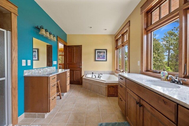 bathroom featuring tile patterned flooring, double sink vanity, and a relaxing tiled tub