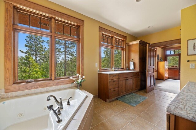 bathroom featuring tiled tub, vanity, tile patterned flooring, and plenty of natural light