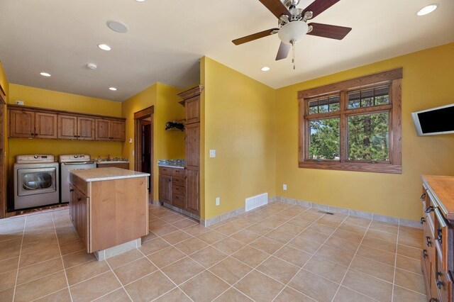 kitchen with light tile patterned flooring, separate washer and dryer, a center island, ceiling fan, and sink