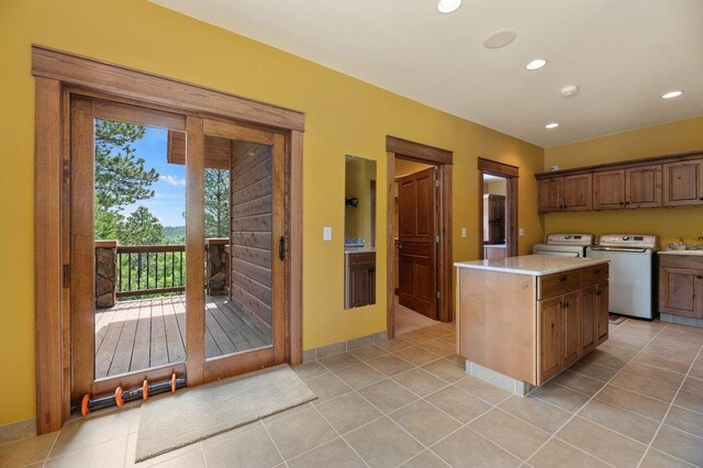 kitchen featuring light tile patterned floors, a center island, washing machine and dryer, and a wealth of natural light