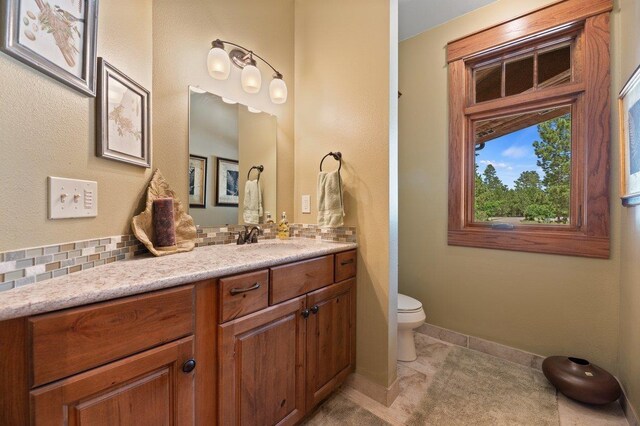 bathroom featuring vanity, backsplash, and toilet