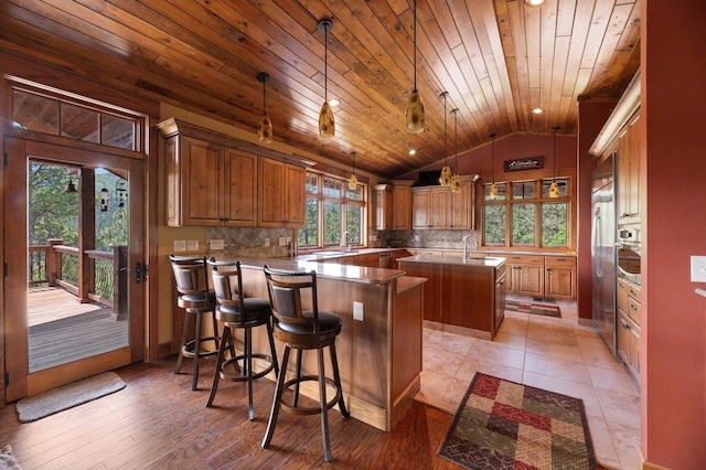 kitchen with hanging light fixtures, an island with sink, light hardwood / wood-style flooring, lofted ceiling, and wood ceiling