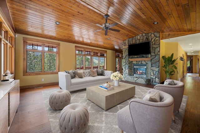 living room with wooden ceiling, wood-type flooring, a stone fireplace, and ceiling fan