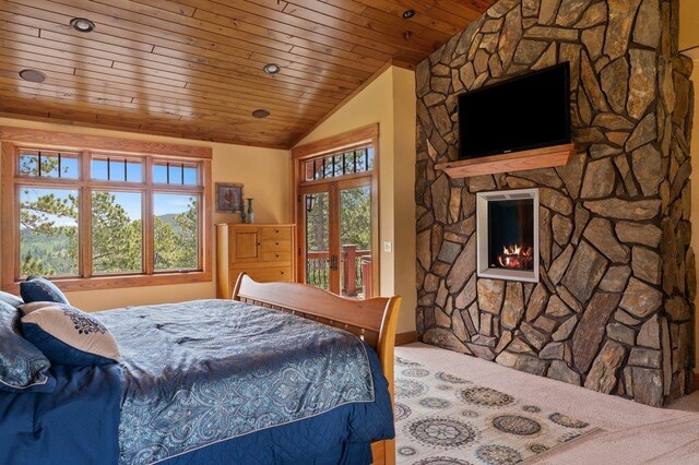 bedroom with a fireplace, vaulted ceiling, multiple windows, and access to exterior