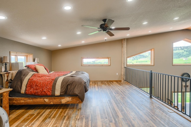 bedroom with a textured ceiling, access to outside, vaulted ceiling, ceiling fan, and hardwood / wood-style flooring