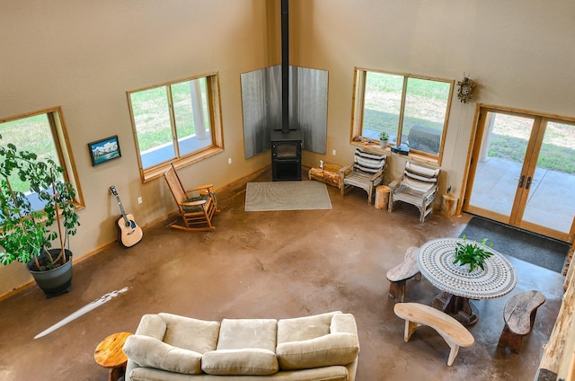 living room with a wood stove, french doors, a high ceiling, and concrete floors