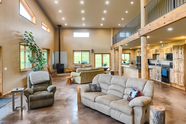 living room with a wood stove, concrete floors, and a high ceiling