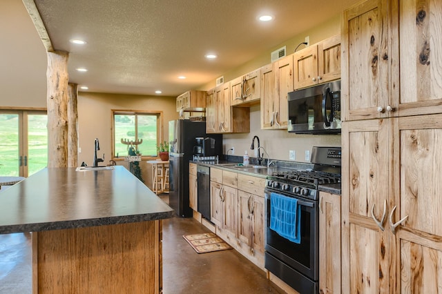 kitchen with a center island, sink, a textured ceiling, light brown cabinetry, and appliances with stainless steel finishes