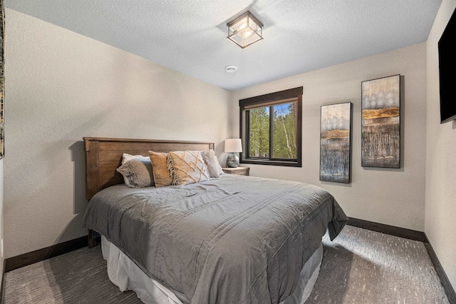 bedroom with dark carpet and a textured ceiling