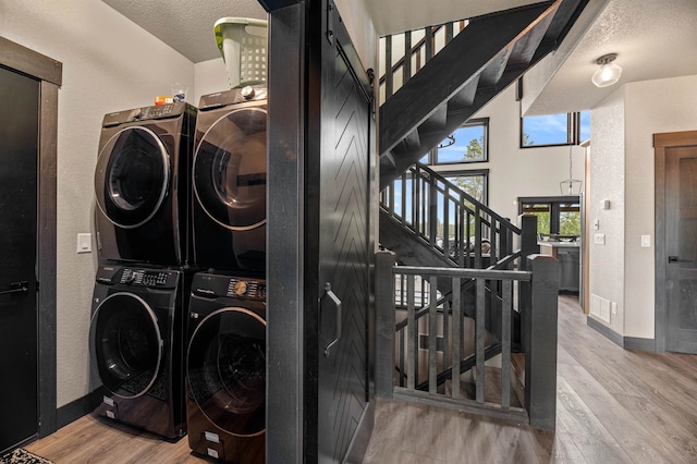 laundry room with separate washer and dryer, light hardwood / wood-style floors, and a barn door