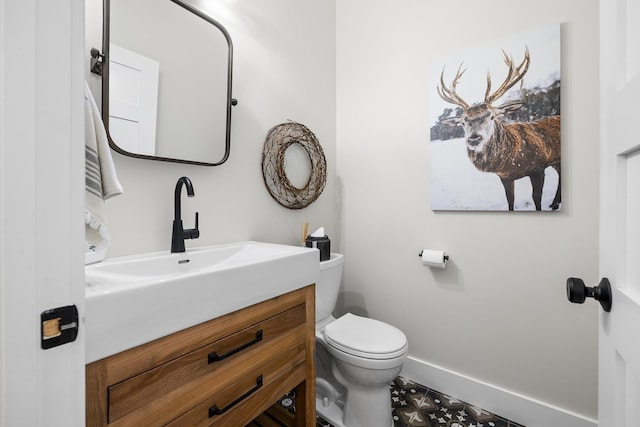 half bath featuring vanity, toilet, and baseboards