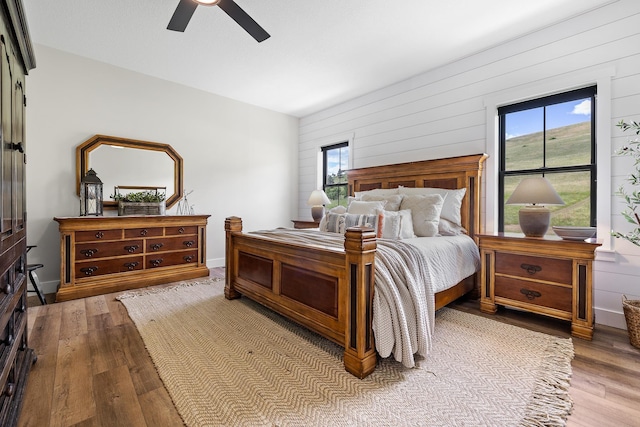 bedroom with ceiling fan, baseboards, and wood finished floors