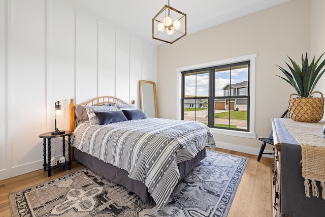 bedroom featuring baseboards, light wood-style floors, and an inviting chandelier