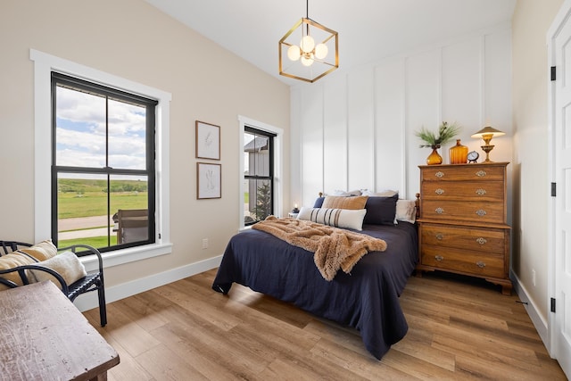 bedroom featuring baseboards, light wood finished floors, and a chandelier