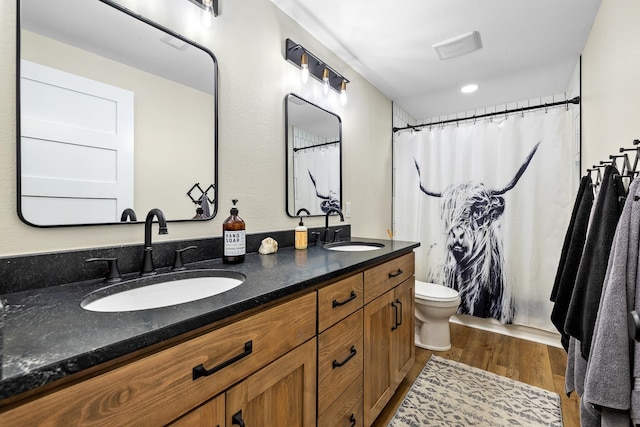 bathroom with toilet, hardwood / wood-style flooring, and double vanity