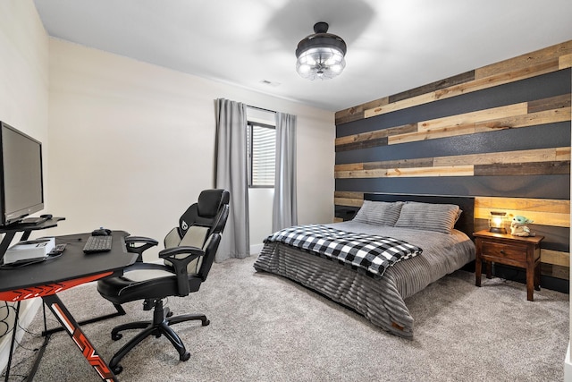 carpeted bedroom featuring visible vents and wooden walls