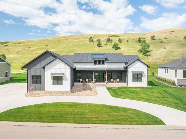 modern farmhouse style home featuring driveway, a front lawn, a standing seam roof, board and batten siding, and metal roof