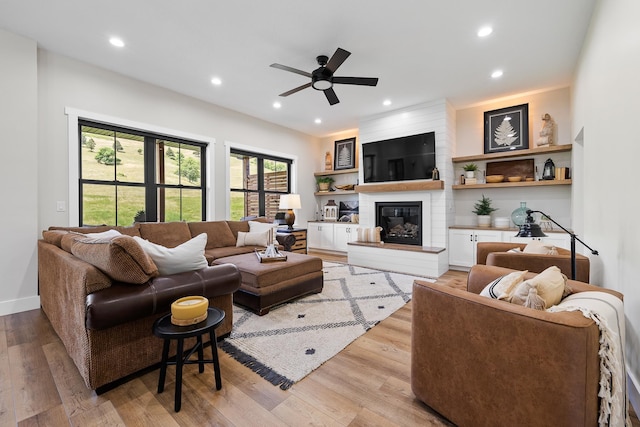 living area featuring a ceiling fan, recessed lighting, light wood finished floors, and a large fireplace